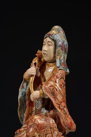 A Japanese Satsuma okimono of Kannon holding a lotus flower