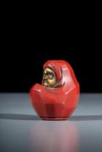 Een rode en vergulde houten netsuke in lakwerk die Daruma