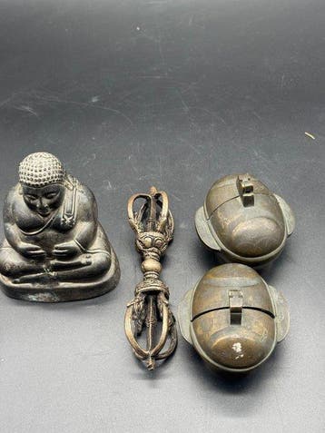 Twee kandelaars, een boeddhistisch standbeeld en een vajra.