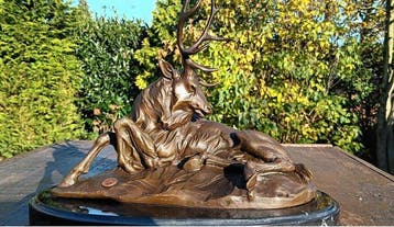 sculptuur, liggend hert met een statig gewei. - 24 cm -