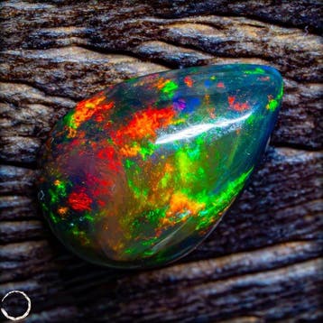 Zwarte opaal cabochon met een intens groen-gouden