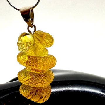 Uitgehouwen slangen- en schedelhanger in Baltisch amber met