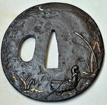 Prachtige zilveren inleg van maan-krekel-insect op een tsuba
