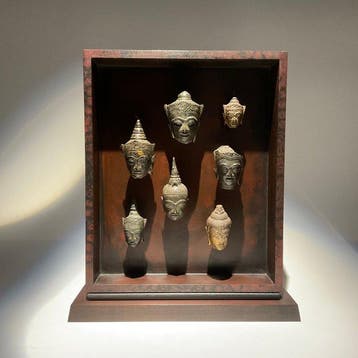 Vitrine met 7 kleine Siamees-bronzen Boeddha-hoofdjes -