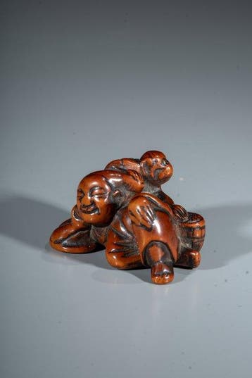 Een netsuke van buxushout van een slapende sarumawashi met