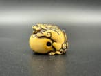 Een netsuke van hertenhoorn met een shishi op een bal, uit