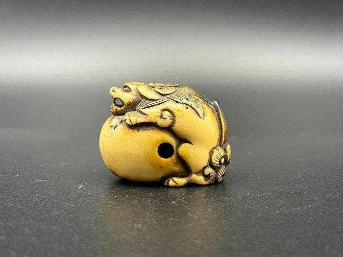 Een netsuke van hertenhoorn met een shishi op een bal, uit, Antiek en Kunst, Antiek | Overige Antiek