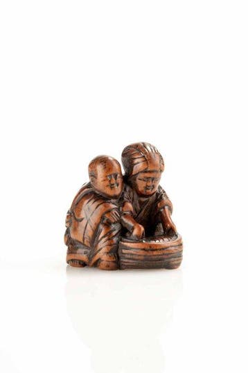 Een Japanse netsuke van buxushout van een knielende moeder