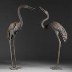 Levensgrote paar tuindecoraties in de vorm van kraanvogels.