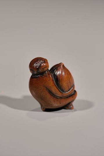 Een zachte netsuke van boxhout in de vorm van een aap met